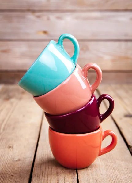 Tasses à café colorées sur table en bois sur fond grunge — Photo