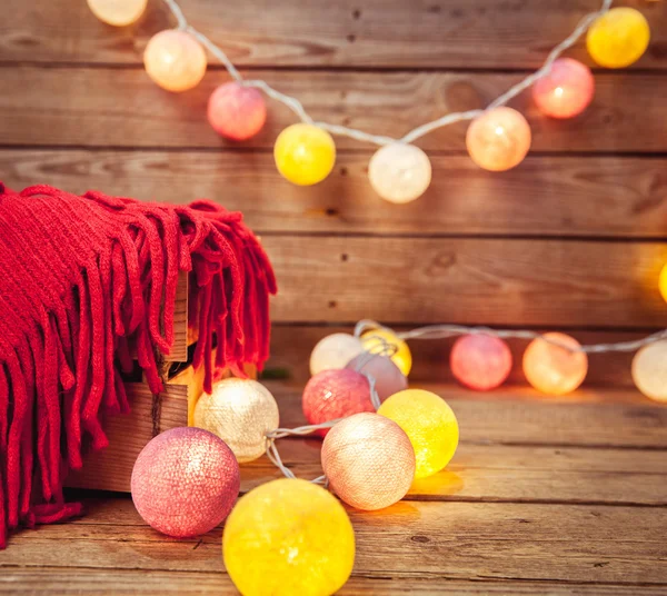 Рождественский набор. Теплое одеяло, свитер, носки, гирлянда и шишка на деревянном фоне — стоковое фото