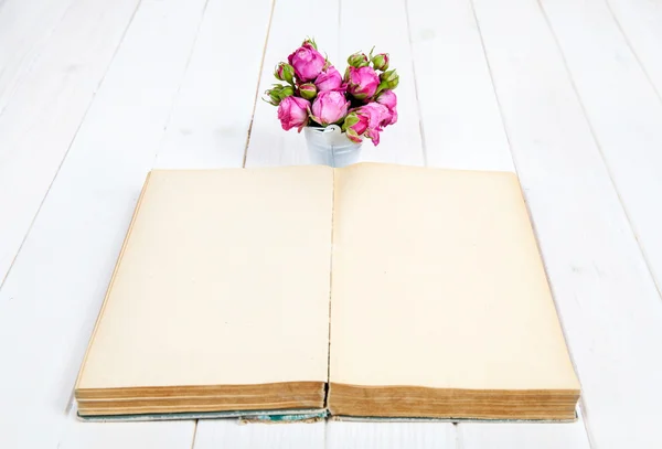 Rozen op een oud boek op witte houten achtergrond. bloemen — Stockfoto