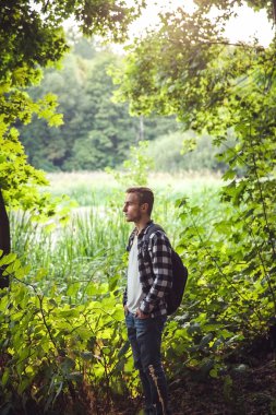 Sırt çantası avare ile genç yakışıklı adam portresi ormanın içinde yürümek