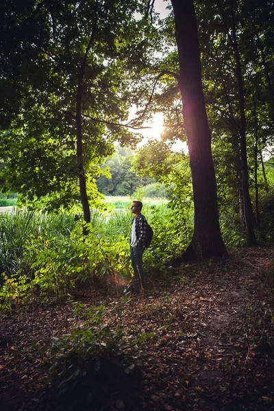 Portrét pohledný mladík s batoh poutník procházka v lese — Stock fotografie