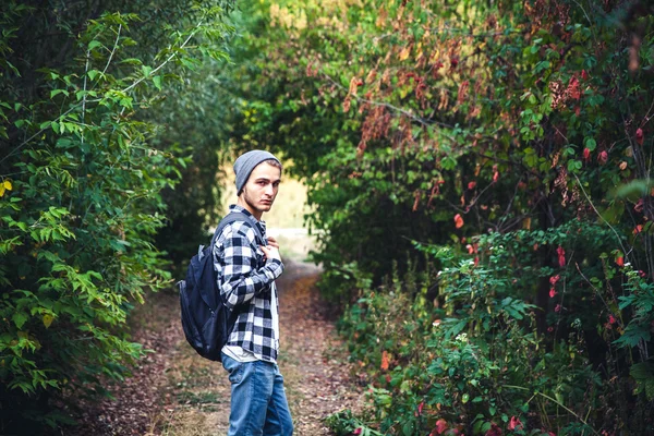 Ritratto di giovane bell'uomo con zaino vagabondo passeggiare nel bosco — Foto Stock