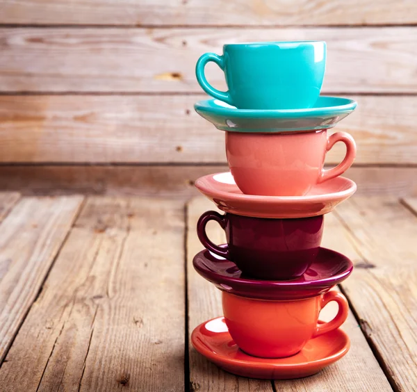 Tasses à café colorées sur table en bois sur fond grunge — Photo