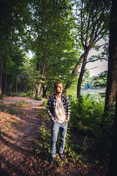 Retrato de un joven guapo con mochila vagabundo caminar en el bosque — Foto de Stock