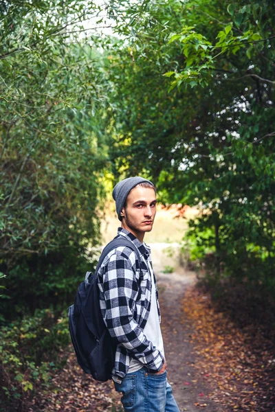 Portrét pohledný mladík s batoh poutník procházka v lese — Stock fotografie