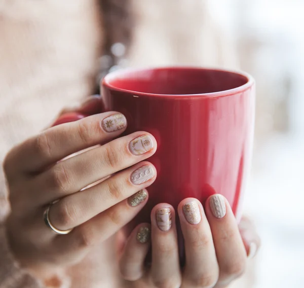 Frau hält eine rote Tasse Kaffee in der Hand. mit einer schönen Winter-Maniküre. Trinken, Mode, Morgen — Stockfoto