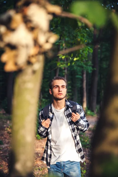 Portrét pohledný mladík s batoh poutník procházka v lese — Stock fotografie
