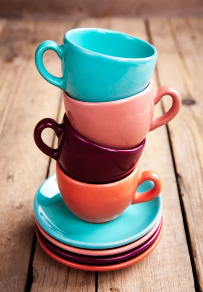 Colorful coffee cups on wooden table over grunge background — Stock Photo, Image