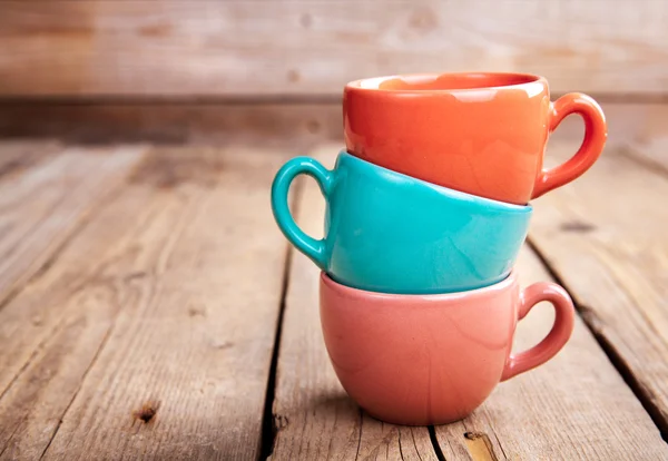 Tasses à café colorées sur table en bois sur fond grunge — Photo