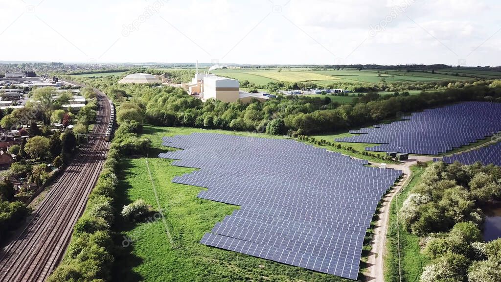 solar energy panels farm and the train railway and industrial factories and agriculture files from aerial view during sunny day.