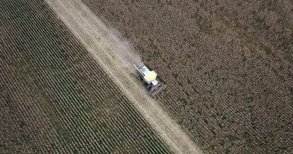 Drone high angle top view of Combine harvester machine while harvesting agricultural fields of grain crops.