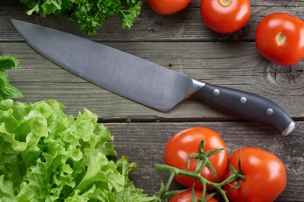 Kitchen knife in table with vegetables — Stock Photo, Image