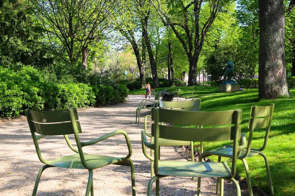 Расслабляющие зеленые стулья в Люксембургском саду в Париже