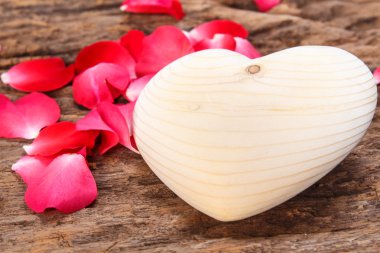 Kırmızı gül ve kalp ahşap tahta üzerinde.