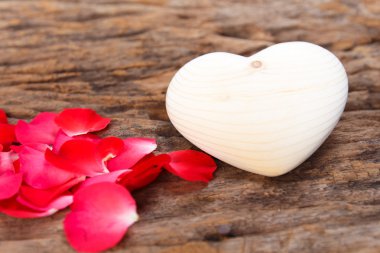 Kırmızı gül ve kalp ahşap tahta üzerinde.