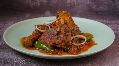 Baharatlı kırmızı körili tavuk soğan halkası ve yeşil biberle süslenmiş..