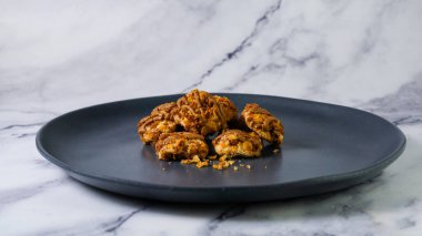 Koyu gri bir tabakta karamel kaplı taze pişmiş, gevrek gevrek kurabiyelerin yakın çekimi..