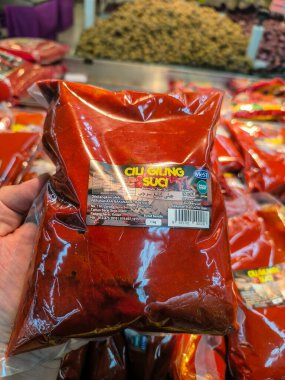 PERAK, MALAYSIA - 22 EKİM 2025: Elinde parlak kırmızı 'Cili Giling Suci' biber macunu paketi var.