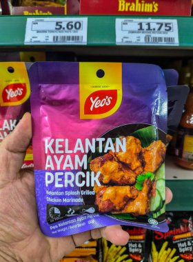 PERAK, MALAYSIA - 22 Ekim 2025: Bir süpermarkette Yeo 'nun Kelantan Ayam Percik salamurasından bir paket tutuyor.