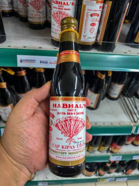 PERAK, MALAYSIA - 22 Ekim 2025: Süpermarket koridorunda Habhal 'ın Tatlı Soya Soya Sosu (Kicap Manis) şişesini tutan.