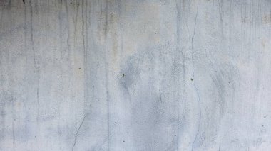 İnce çatlaklar, dikey su lekeleri ve gri tonlarda pürüzlü, dokulu bir yüzey içeren sıkıntılı, yıpranmış beton bir duvarın yüksek çözünürlüklü görüntüsü..