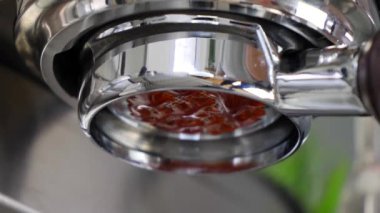 Espresso makinesi dipsiz iskele filtresi. Düşük açılı. Kahve damlaları dökerken yakın görüş..