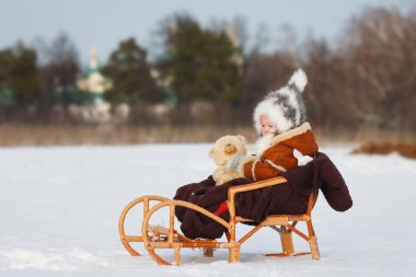 Çocuk bir kızak üzerinde oturur