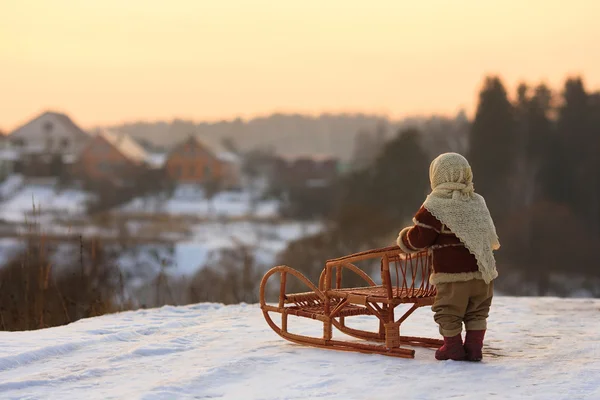 Ребенок с санями стоит на холме — стоковое фото