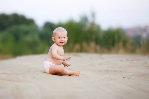 Het kind zit op het zand in de zomer — Stockfoto