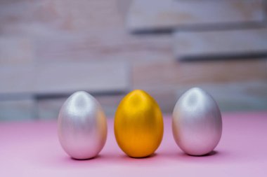 Yüzeyde üç yumurta duruyor, gümüş ve altın.