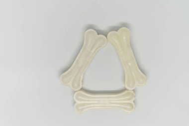 Beyaz arka planda vitaminleri olan, üçgen şeklinde bir köpek için yapay kemik.