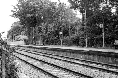 Brundall, Norfolk, İngiltere - 22 Temmuz 2020. Norfolk kırsalındaki Brundall Bahçeleri 'ndeki demiryolu hattının ve beton platformun siyah ve beyaz resimli resmi.