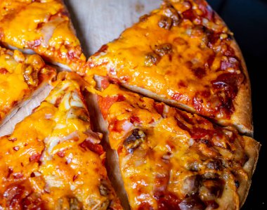 Dilimlenmiş peynir ve domatesli pizzayı ahşap doğrama tahtasına yakın tut.