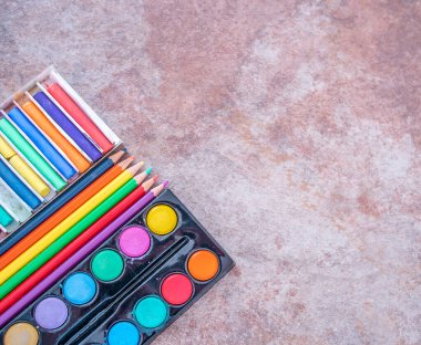 3 düz su boyası, boyama kalemleri ve renkli tebeşirler düz bir arkaplan üzerinde kopya alanı ile