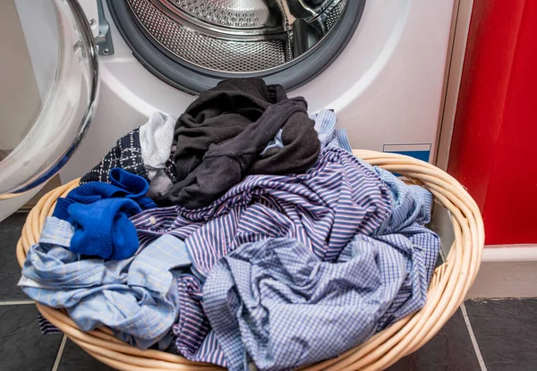 7 An out of focus wicker basket full of wet laundry in front of a washing machine in sharp focus