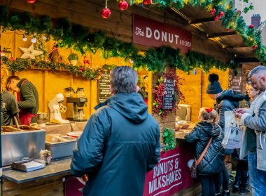 York, İngiltere, - 23 Kasım 2019. Bir annenin, genç kızına, York 'taki Noel pazarındaki bir sokak yemekçisinden sıcak çörek alırken çekilmiş resimli bir fotoğrafı.