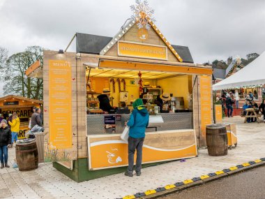 Derbyshire, İngiltere - 26 Kasım 2019. Yılbaşı pazarındaki seyyar kahve dükkanından kahve alan bir adamın illüstrasyon fotoğrafı. 