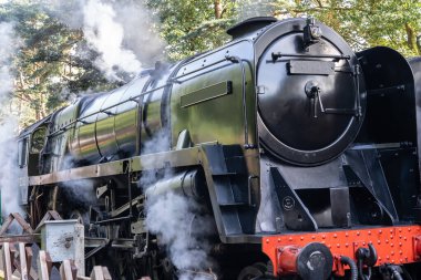 4Sheringham, Norfolk, İngiltere - 14 Eylül 2019. Yolcularını bıraktıktan sonra bir tren istasyonunda basınç ve buhar salan siyah bir buhar treninin resimli editör fotoğrafı.