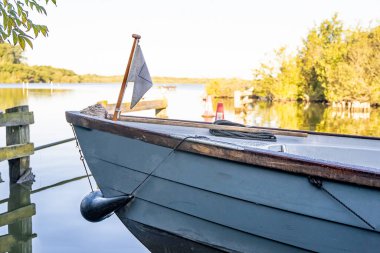 Front end view of a moored boat with an out of focus lake in the distance in rural Norfolk in the Norfolk Broads clipart