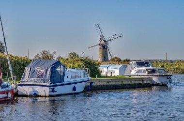 A  view up Thurne Dyke towards the distant windmill in the heart of the Norfolk Broads. Captured on a bright and sunny day. clipart