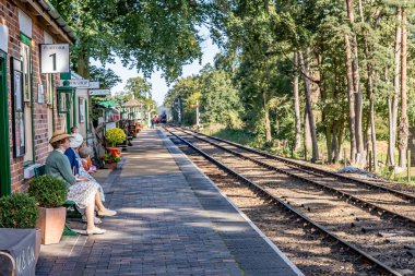  Sheringham, Norfolk, İngiltere - 14 Eylül 2019. 1940 'ların Holt ve Sheringham kasabasında serbest ve her yıl yapılan 40' lı yılların açılışında Holt tren istasyonunda buharlı tren bekleyen 40 'lı yılların elbiseli iki bayanın resimli resmi.