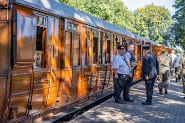  Sheringham, Norfolk, İngiltere - 14 Eylül 2019. Norfolk Poppy Hattı 'ndaki Holt İstasyonu' ndaki geleneksel ahşap tren vagonunun yanındaki kondüktörlerin serbest ve tüm yıllık 40 'lı yılların serbest hafta sonları boyunca yayınlanan resimli fotoğrafı..