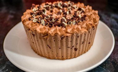 Donmuş çift katlı çikolatalı gateau 'nun, mermer kaplı siyah bir mutfak atölyesinde beyaz bir tabakta yakın plan fotoğrafı.