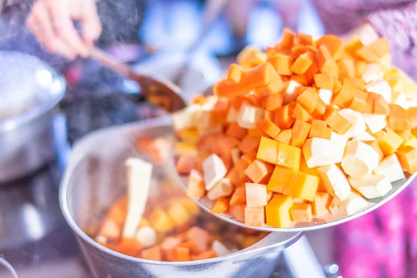 Ev aşçısı, sağlıklı ve besleyici bir vejetaryen kırmızı biber güveci yapmak için paslanmaz çelik bir soğan ve sarımsak tavasına doğranmış sebze ekliyor.