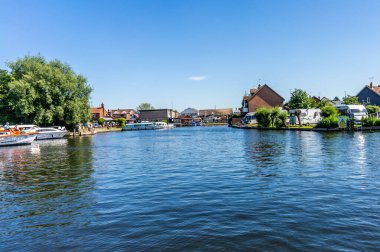 Wroxham, Norfolk, İngiltere - 22 Haziran 2019. Açık ve güneşli bir günde, Wroxham 'dan halka açık köprüde Bure Nehri' nin yukarısına bakan bir manzaranın resmedilmiş bir resmi.