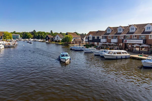 Wroxham, Norfolk, İngiltere - 22 Haziran 2019. Norfolk Broads 'un kalbinde popüler bir turizm merkezi olan Wroxham köyündeki yol köprüsüne doğru giden küçük bir teknenin illüstrasyon fotoğrafı.
