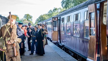 Holt, Norfolk, İngiltere - 14 Eylül 2019. 1940 'ların tarzında giyinmiş bir grup insanın resimli bir fotoğrafı, Holt İstasyonu' na vardıktan sonra buharlı trenden inerek tüm 40 'ların hafta sonlarına açık ve ücretsiz giriş yaptı.