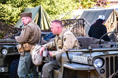 Holt, Norfolk, İngiltere - 14 Eylül 2019. Holt 'ta 40' lı yılların tüm hafta sonlarına bedava giriş ve çıkış yapan Amerikan askeri araçları arasında Amerikan asker üniforması giymiş erkeklerin resimli bir fotoğrafı.
