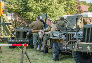Holt, Norfolk, İngiltere - 14 Eylül 2019. Holt 'ta 40' lı yılların tüm hafta sonlarına giriş ve çıkış özgürlükleri sırasında ABD askeri araçları arasında ABD askeri üniformalı erkeklerin resimli bir resmi.