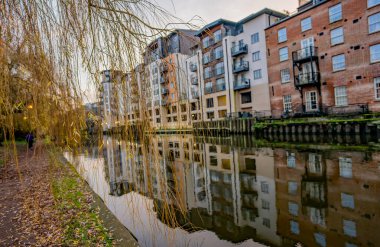 Norwich, Norfolk, İngiltere - 29 Aralık 2019. Nehir boyunca uzanan yolda, nehir kenarındaki pahalı daireler, daireler ve çatı katlarıyla birlikte, seçici bir odak noktasının resimli bir resmi.